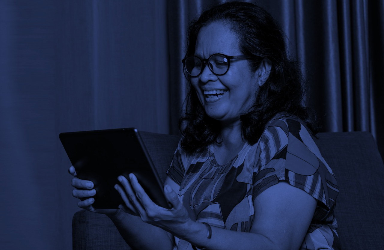 Mujer adulta sonriendo mientras aprende en una tableta: educación virtual para adultos